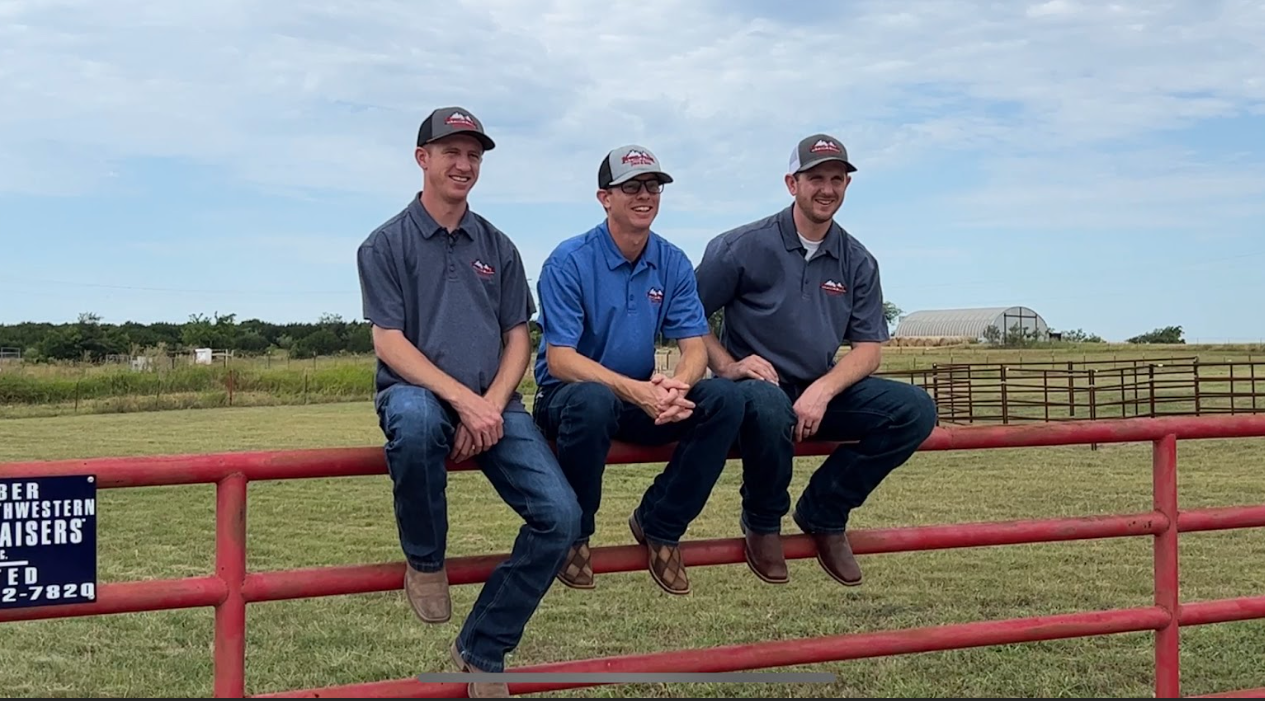 3 men sitting on a pipe fence