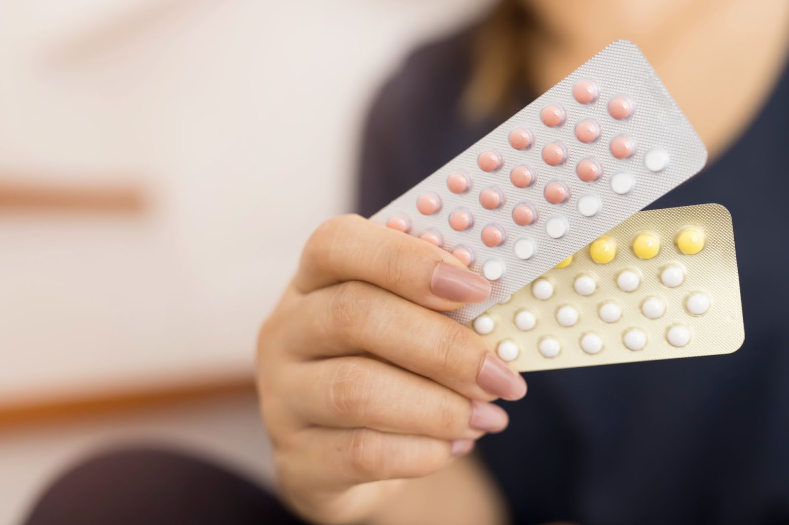 žena drží rôzne druhy hormonálnej antikoncepcie v tabletkovej forme
