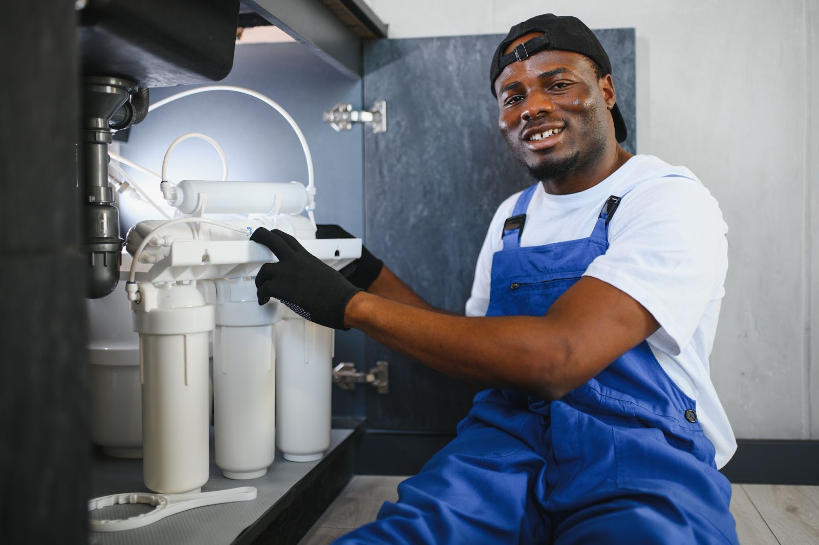 African American plumber replacing a home water filter system.