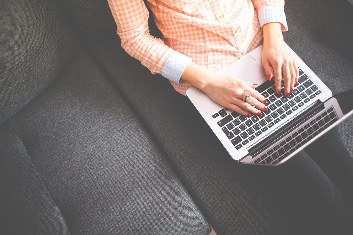 Free Person Sitting on Gray Sofa While Using Macbook Stock Photo