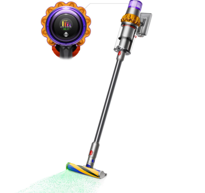 A Dyson cordless vacuum cleaner with a sleek silver and metallic design. The image shows both a close-up of the digital display screen with a purple and orange circular bezel, and the full-length vacuum in an upright position. The vacuum head features a multi-colored cleaning brush and appears to be in action with a light green cleaning pattern visible on the floor beneath it. The design elements include purple, orange, and metallic accents throughout the device.