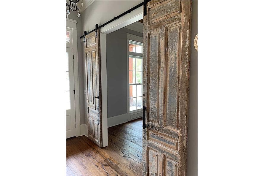 A rustic double barn door opens to a quiet study.