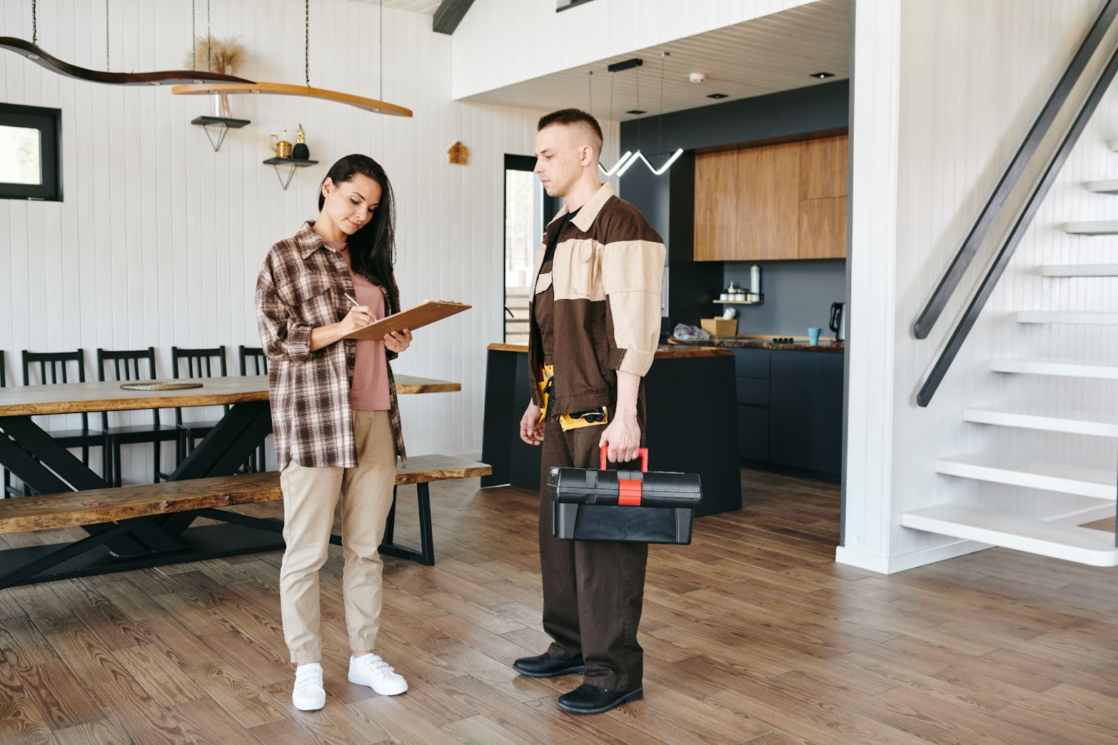 Repair man next to a woman signing a form on a clipboard. 