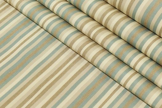 A close-up of acrylic fabric in stripes of beige and light blue.
