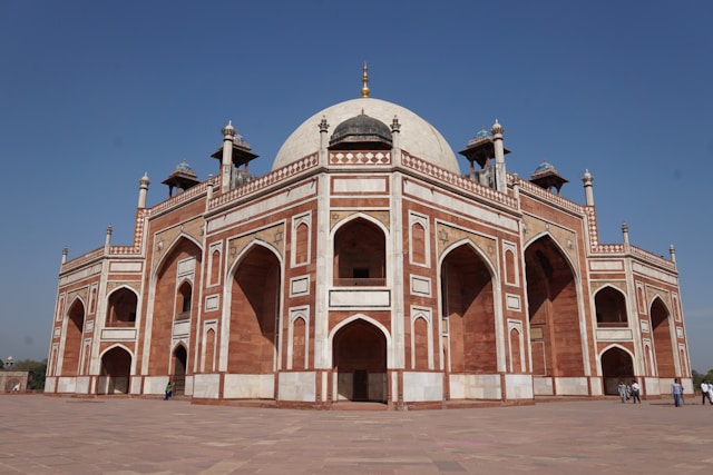 A wide-angle view of Humayun's Tomb in Delhi, India, highlighting its symmetrical architecture with red sandstone and white marble.