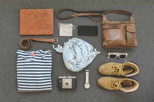 Free Vintage travel essentials flat lay with leather bags, shoes, camera, and clothing. Stock Photo