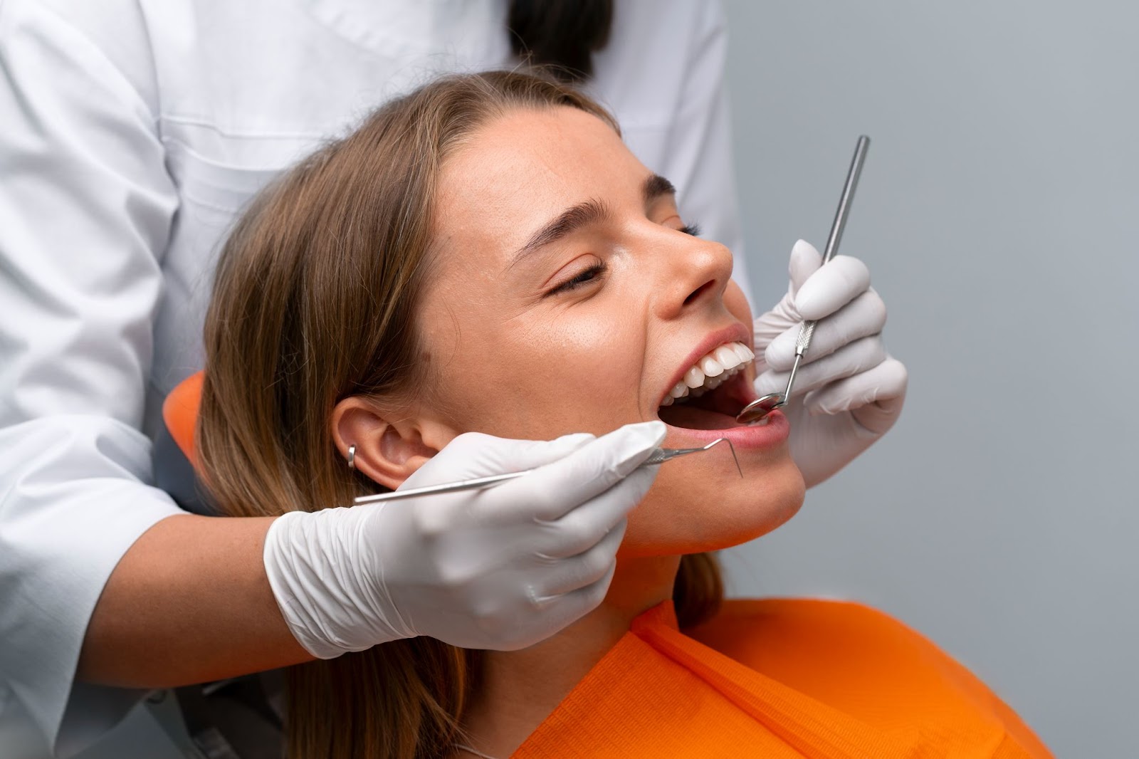 Dentist assessing a female patient’s teeth during a consultation for dental veneers.