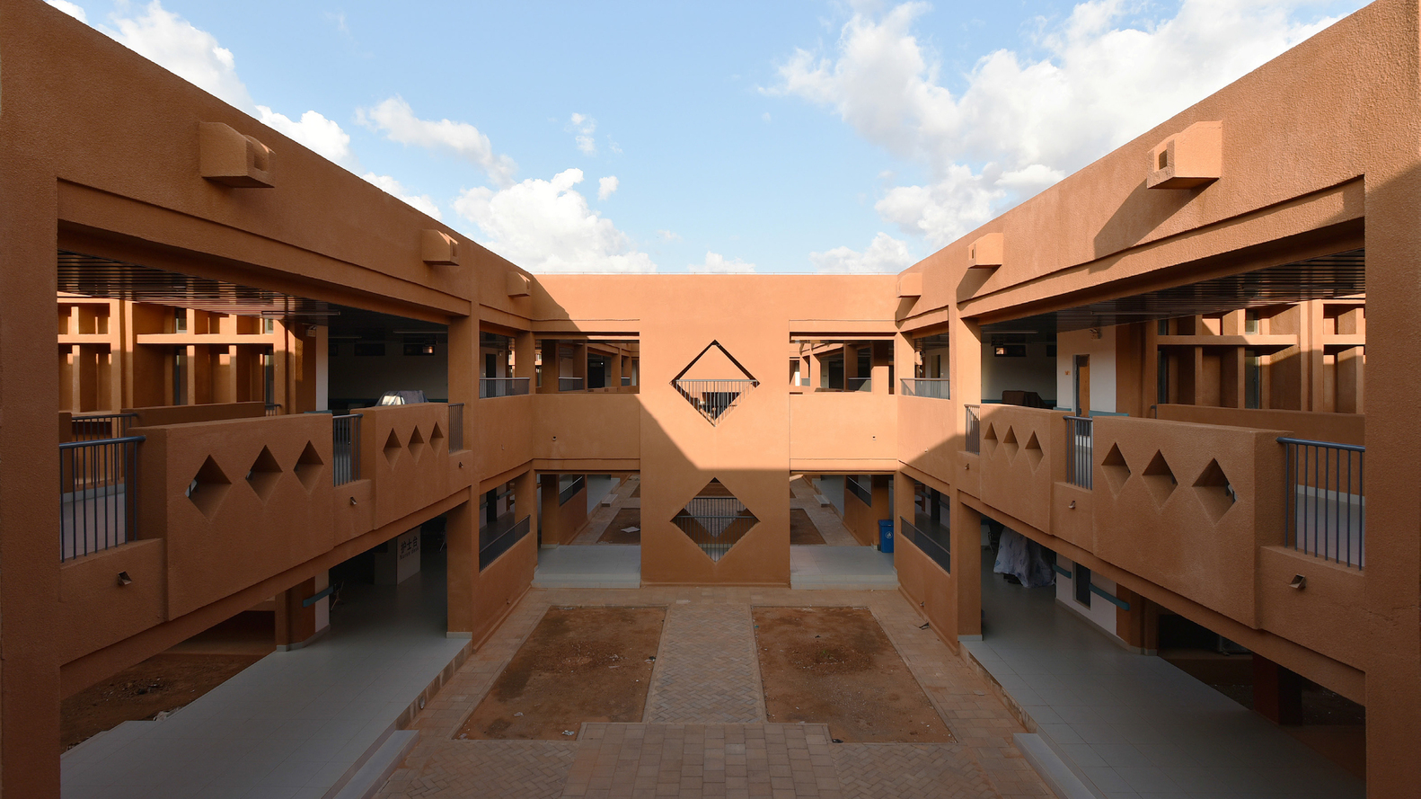 A spacious, open courtyard in a building with terracotta walls and geometric designs.