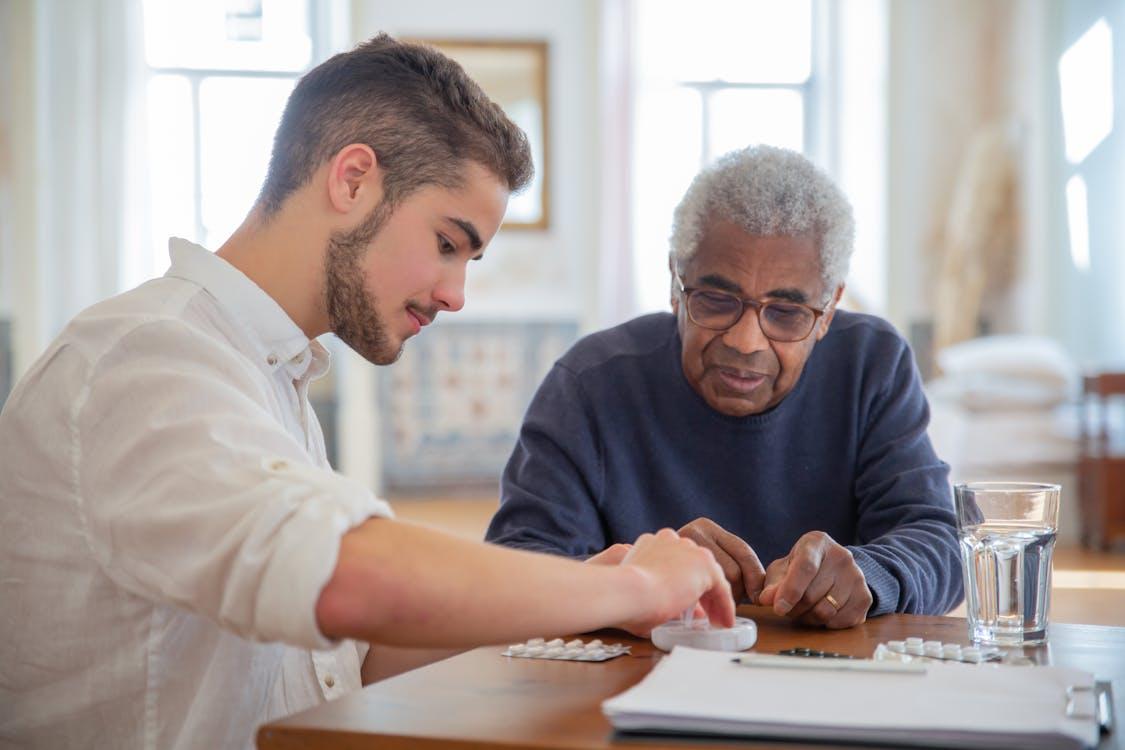 Free A Man in Blue Sweater Sitting Beside Man in White Long Sleeves Stock Photo