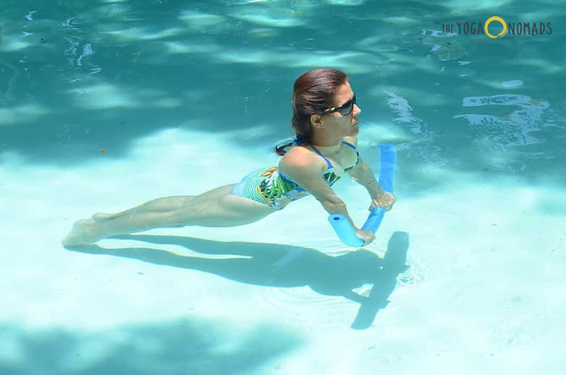 person is doing the upward dog yoga pose inside a pool.