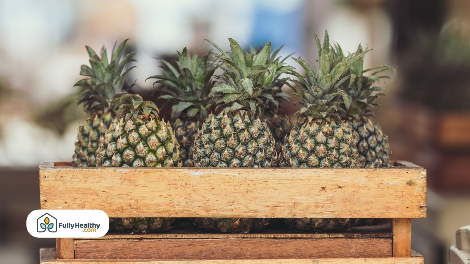 Fresh pineapples arranged in wooden crate at a local market stand