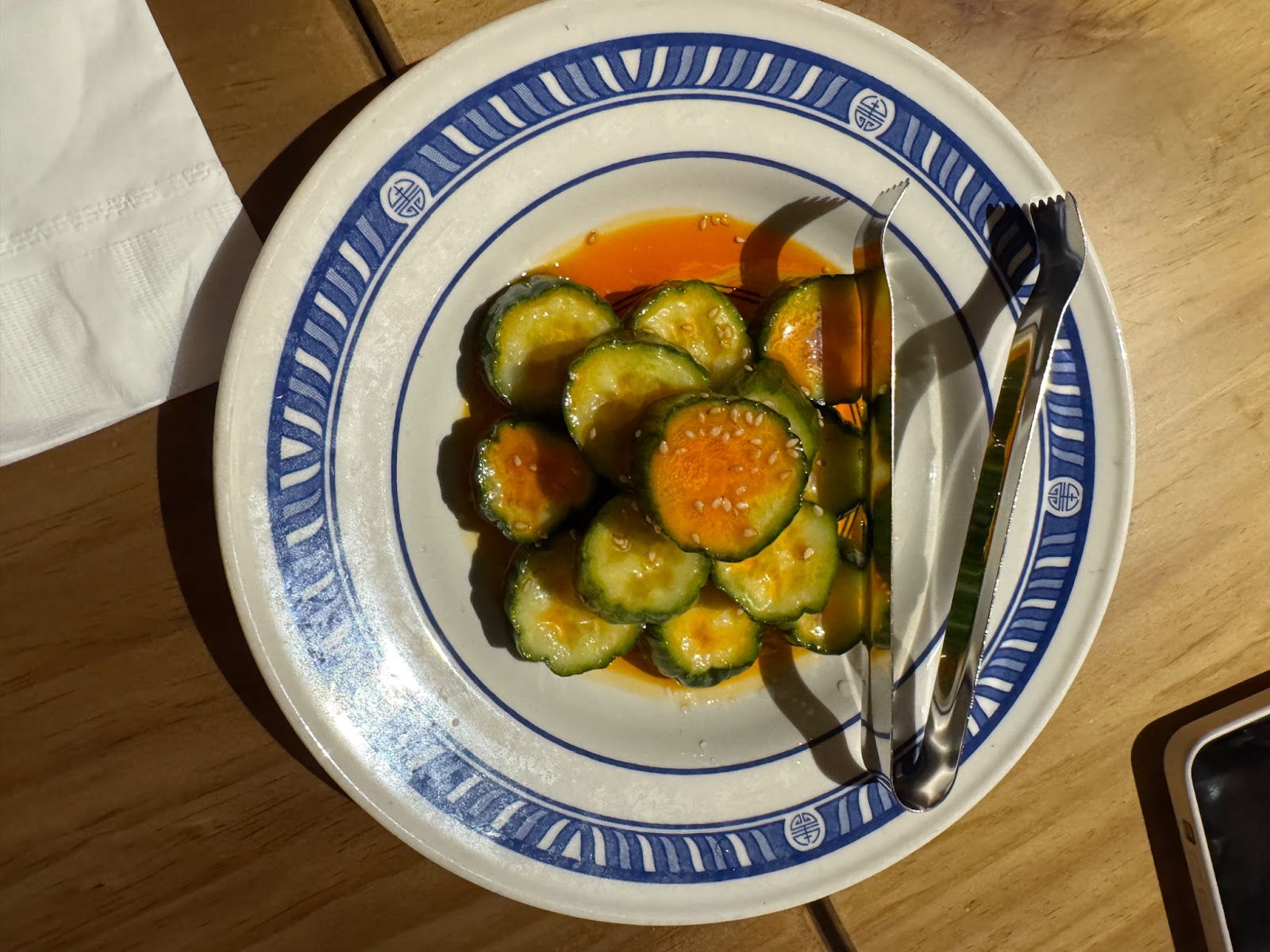 Cold cucumber salad with chili oil and sesame seeds in a white china plate.