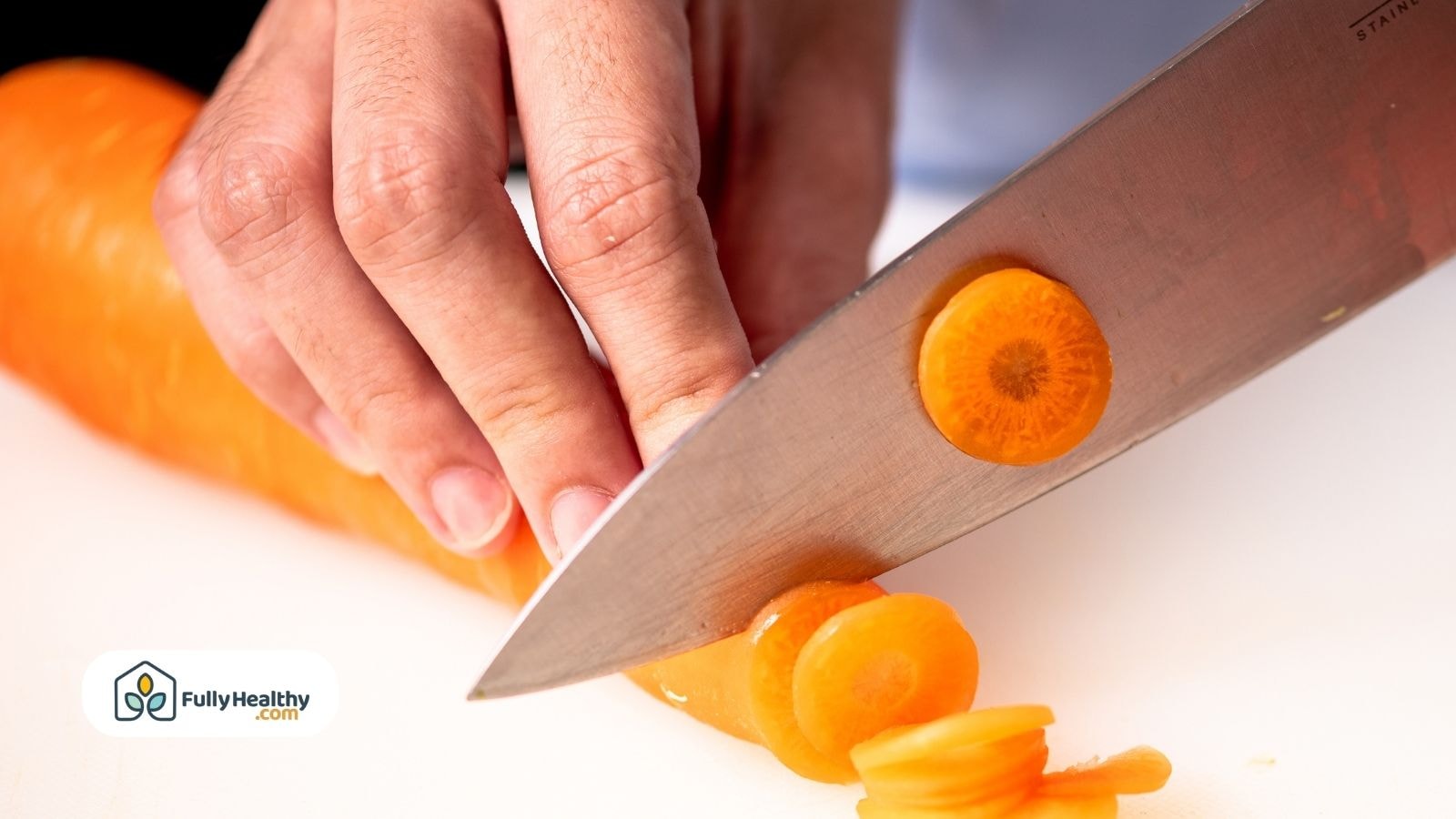 Close-up of hand slicing carrot with sharp knife