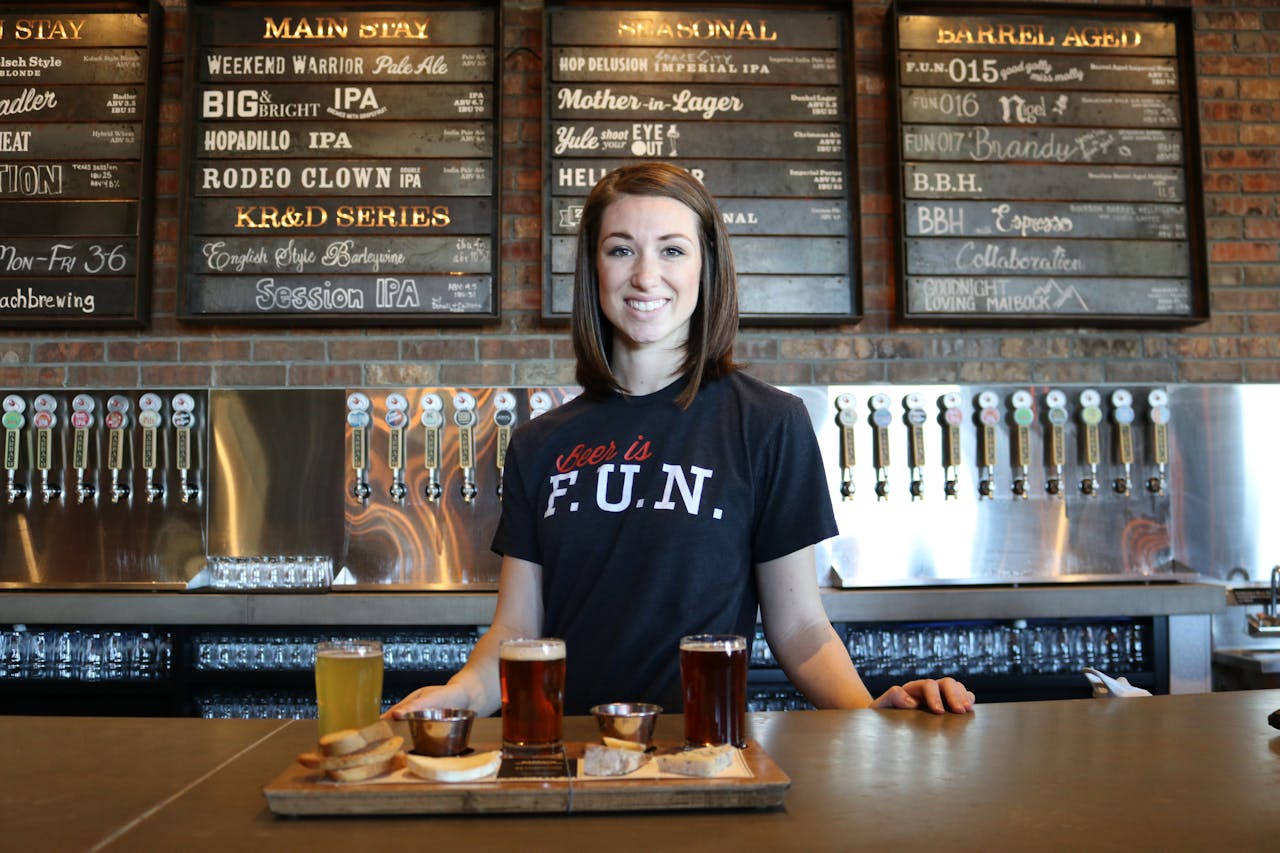 Smiling bartender in a craft beer pub, representing how to manage small business in the hospitality industry with customer service and product offerings.