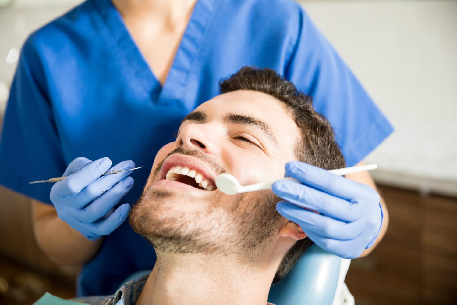 Homem no destista sorrindo por estar cuidando da sáude bucal