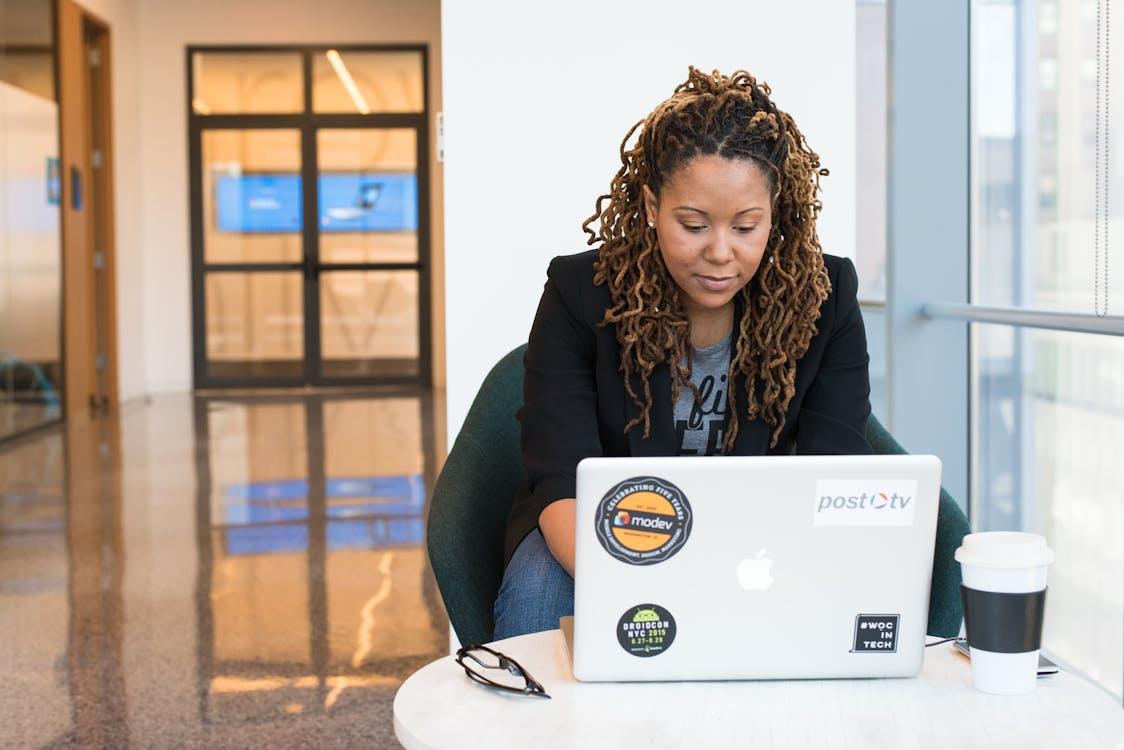 Free A woman focused on her laptop in a modern office environment, signifying tech and business connection. Stock Photo