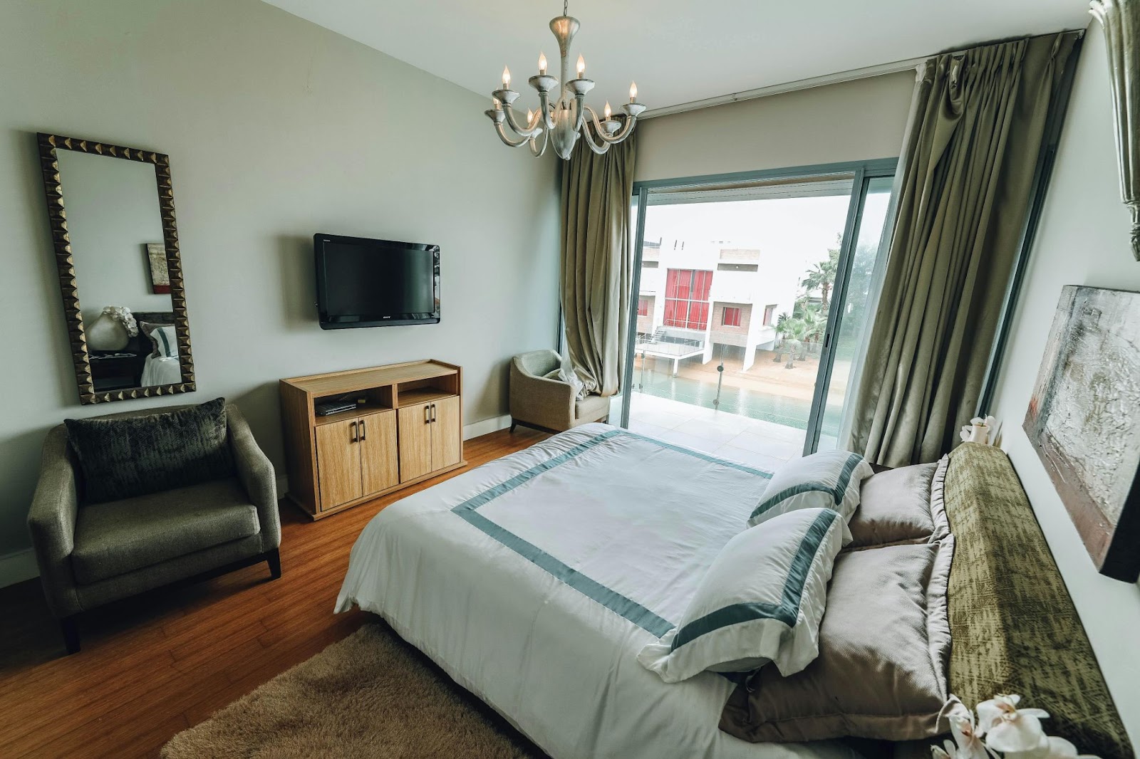 This image depicts elegant glass doors in a bedroom leading out to a balcony, offering a view of the surrounding landscape.