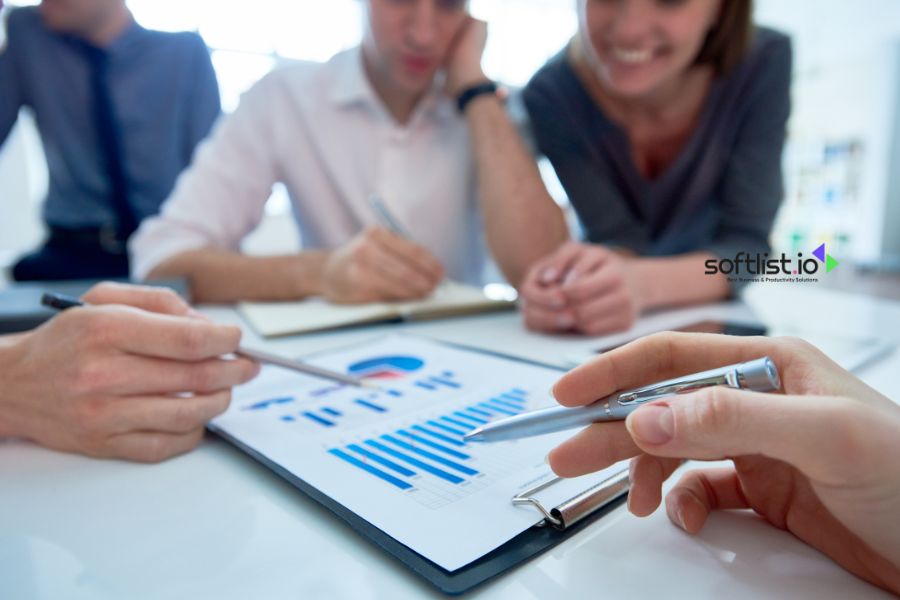 Group of people analyzing charts and data at a meeting.