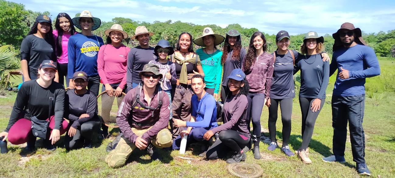 Grupo de pessoas na grama posando para fotoDescrição gerada automaticamente