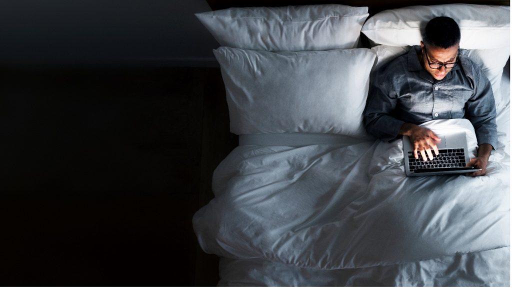 A person using a computer on a bed affects how much sleep do you need