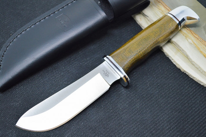 An image showing the Buck Skinner Pro hunting knife, which features a drop point CPM-S35VN blade, an olive drab green Micarta handle, and a leather sheath with a belt clip.