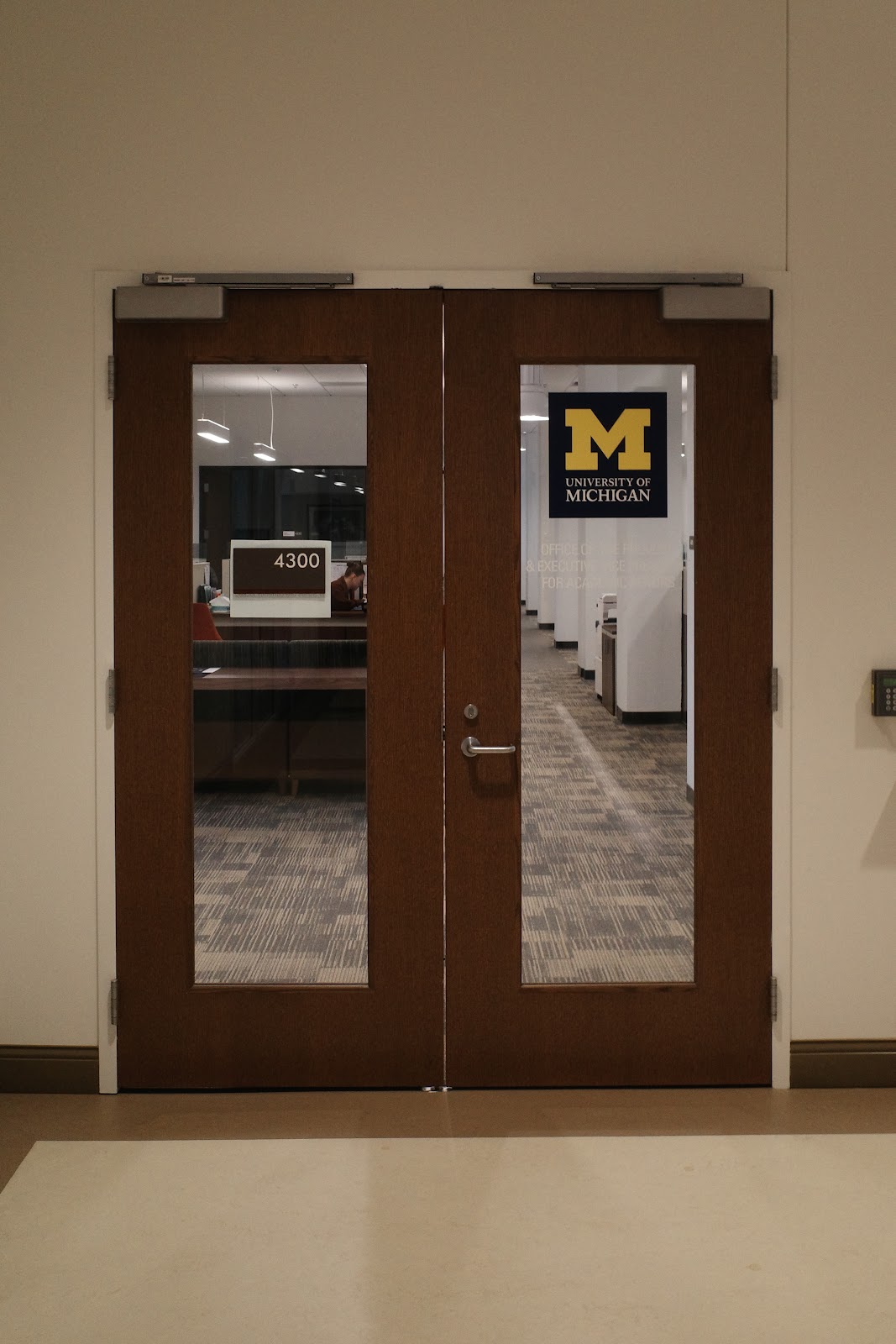 Nondescript door to offices with block M “University of Michigan” sign in window. Door label reads “4300.”
