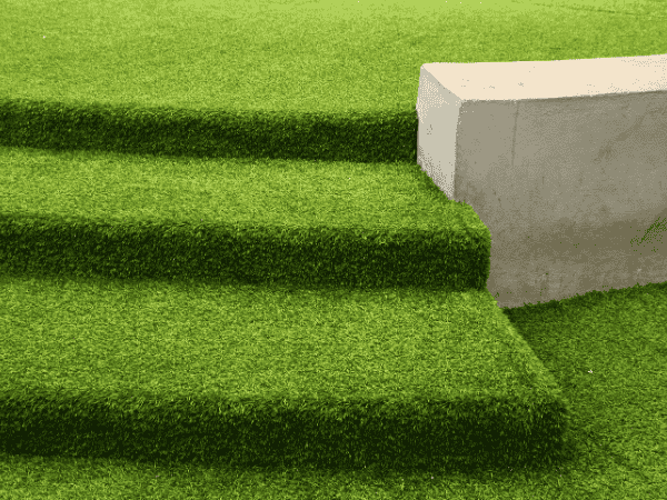 Artificial grass steps beside a concrete wall – is artificial grass safe for outdoor use?