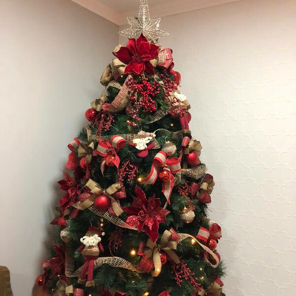 Árvore de Natal decorada com laços, enfeites e uma estrela no topo.