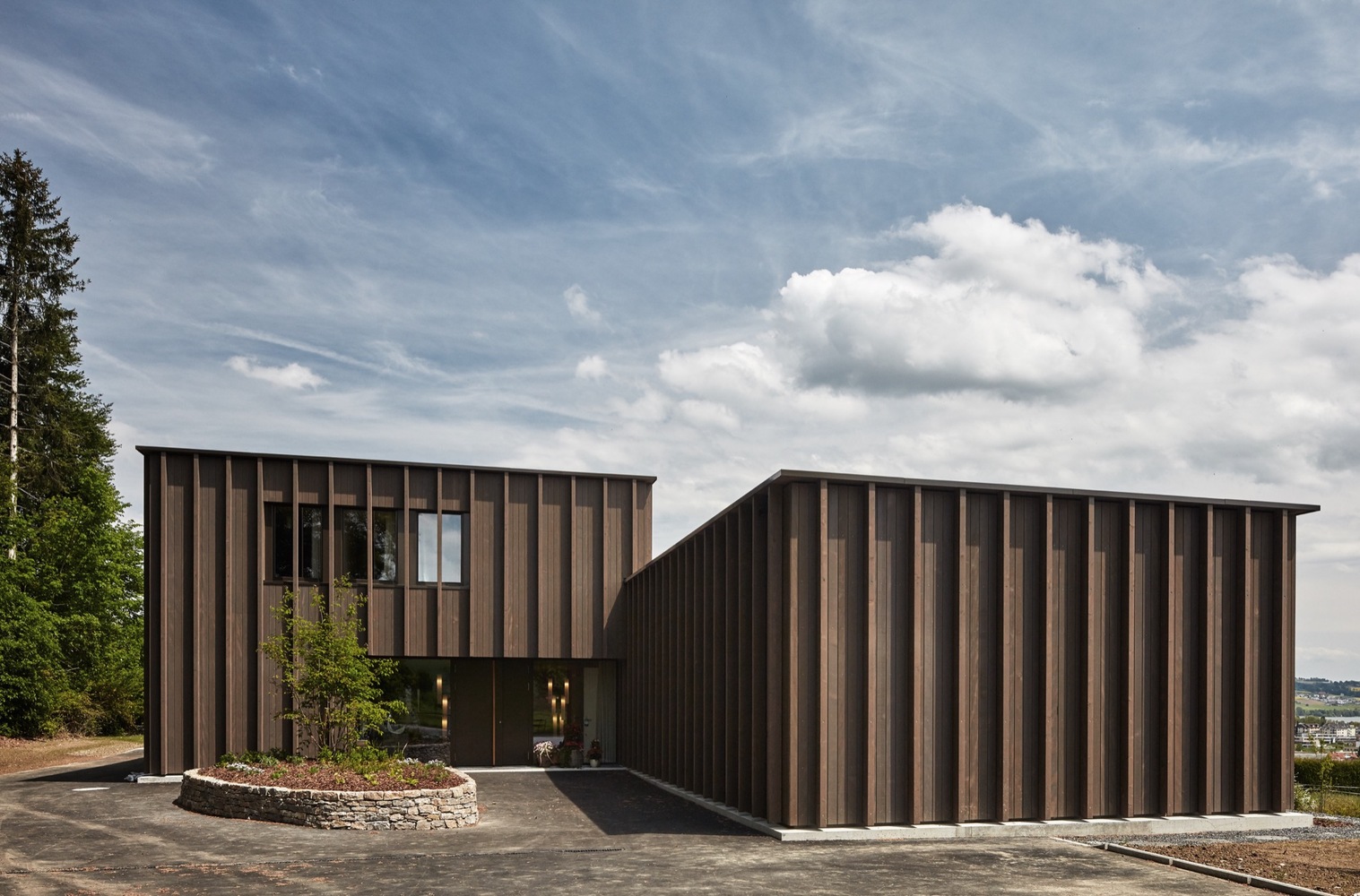 A modern building with dark vertical wooden panels, featuring a two-part structure akin to thoughtful hospital design.