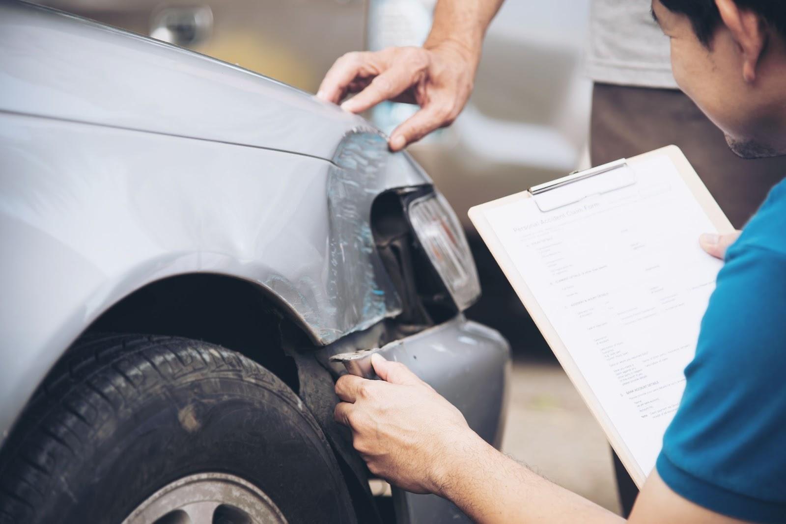 A person holding a clipboard and looking at a car  Description automatically generated