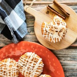 Pumpkin muffins on an orange plate with cinnamon sticks.