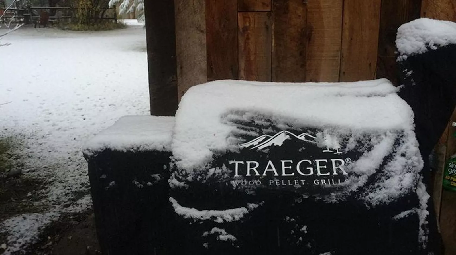 A Traeger grill with cover that has snow accumulating on it.