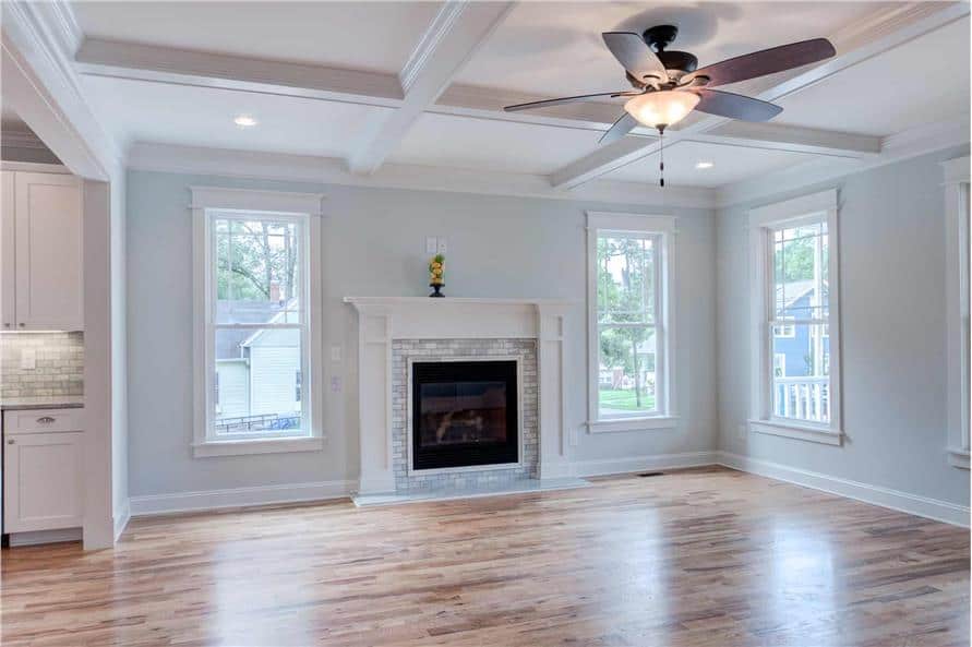 Great room with a coffered ceiling, hardwood flooring, and a fireplace flanked by windows.