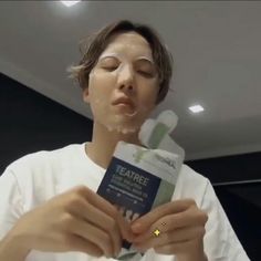 This  contain an image of J-Hope holding up a package of tea tree facial mask on her face and looking at it