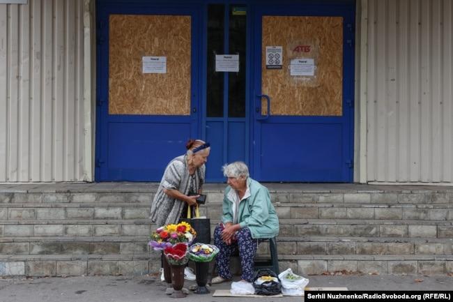 Жінки біля зачиненого супермаркету продають квіти й городину. У Покровську зачинені всі великі супермаркети і ТЦ, працюють лише невеличкі продуктові магазини