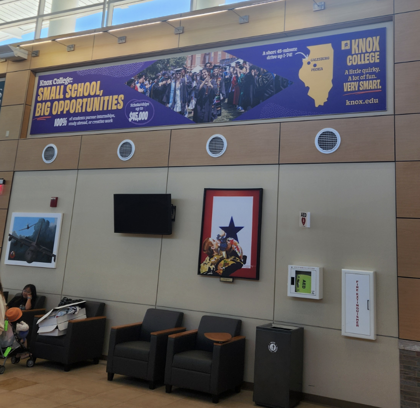 Large banner advertisement promoting enrolling at Knox College in waiting area in a airport terminal.