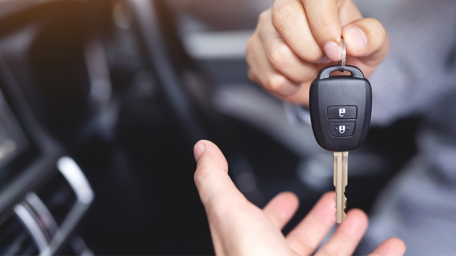 A car locksmith is giving a duplicate car key to a client.