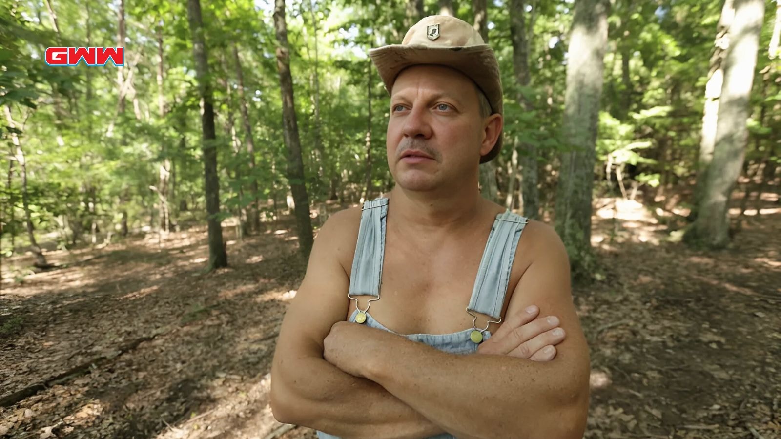 Tim Smith wearing a hat, gazing thoughtfully into the distance in the woods.