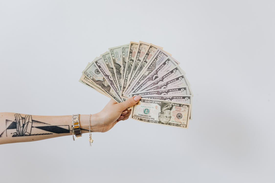 A female holding a lot of money in a fan shape.