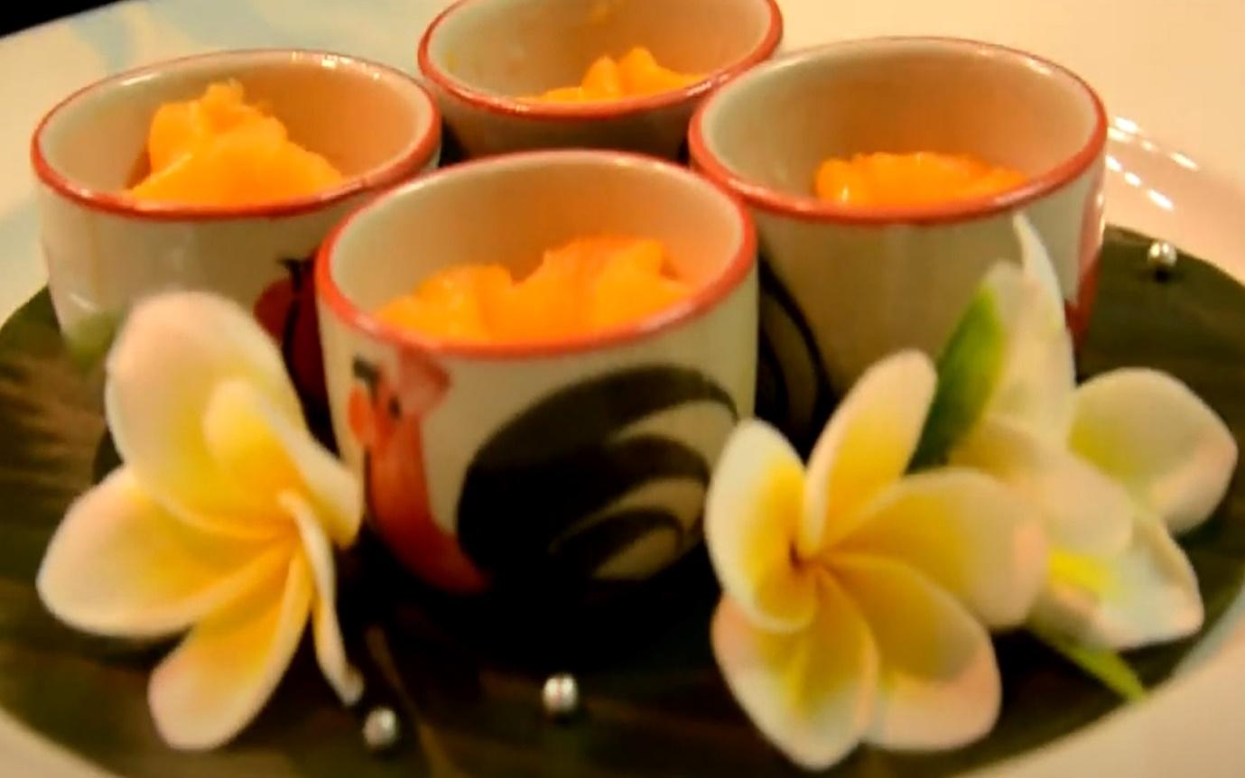 A group of cups with orange food on a plate with flowers

Description automatically generated