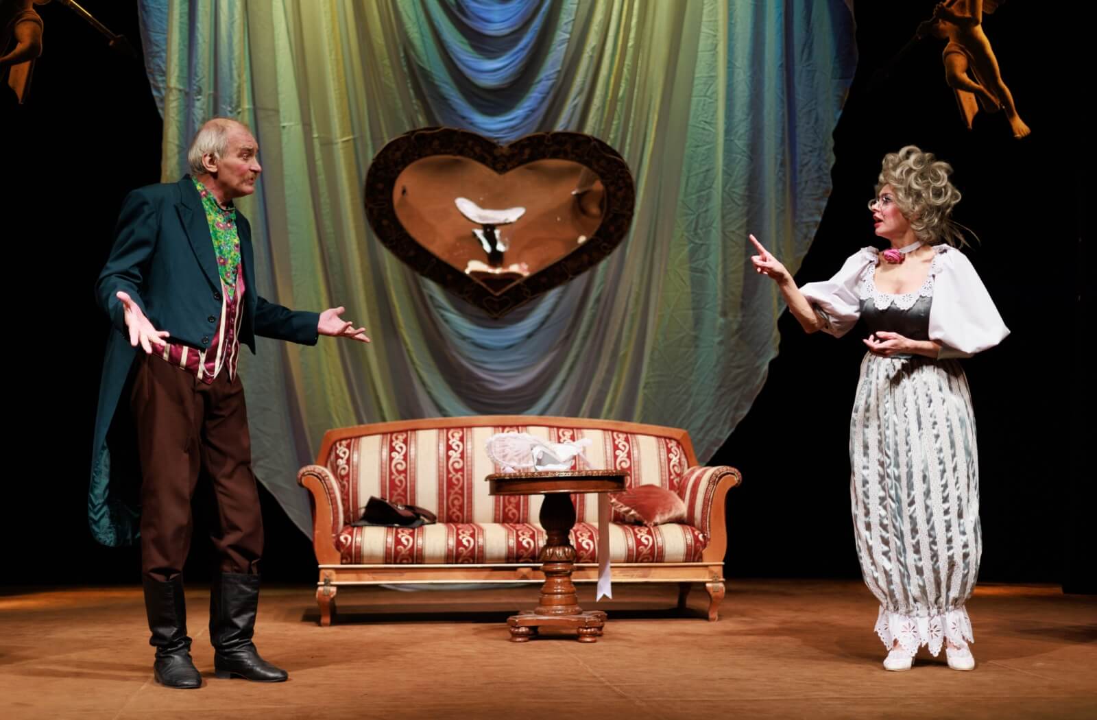 Two seniors in costume on stage in the middle of a scene of a local theater production