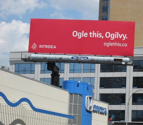 Red billboard with white text reading: Ogile this, Ogilvy. with the Interidea logo