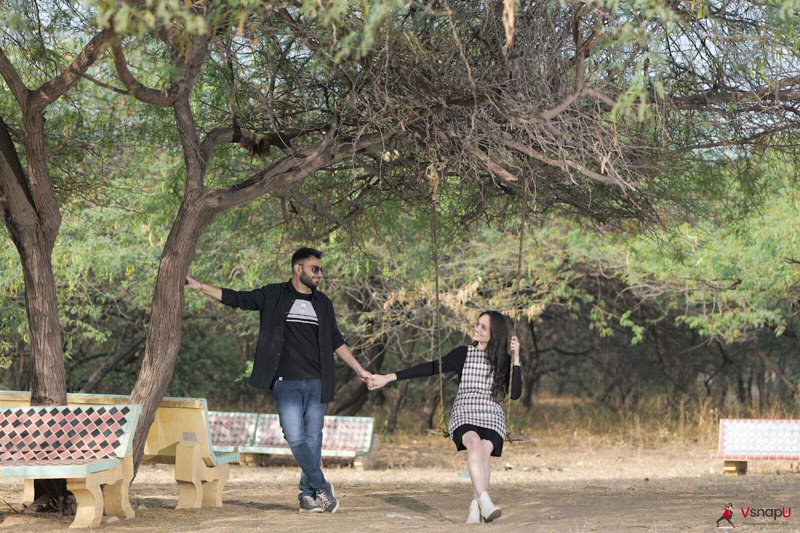 Pre-birthday photoshoot with bride sitting in a swing and groom standing and holding her hand