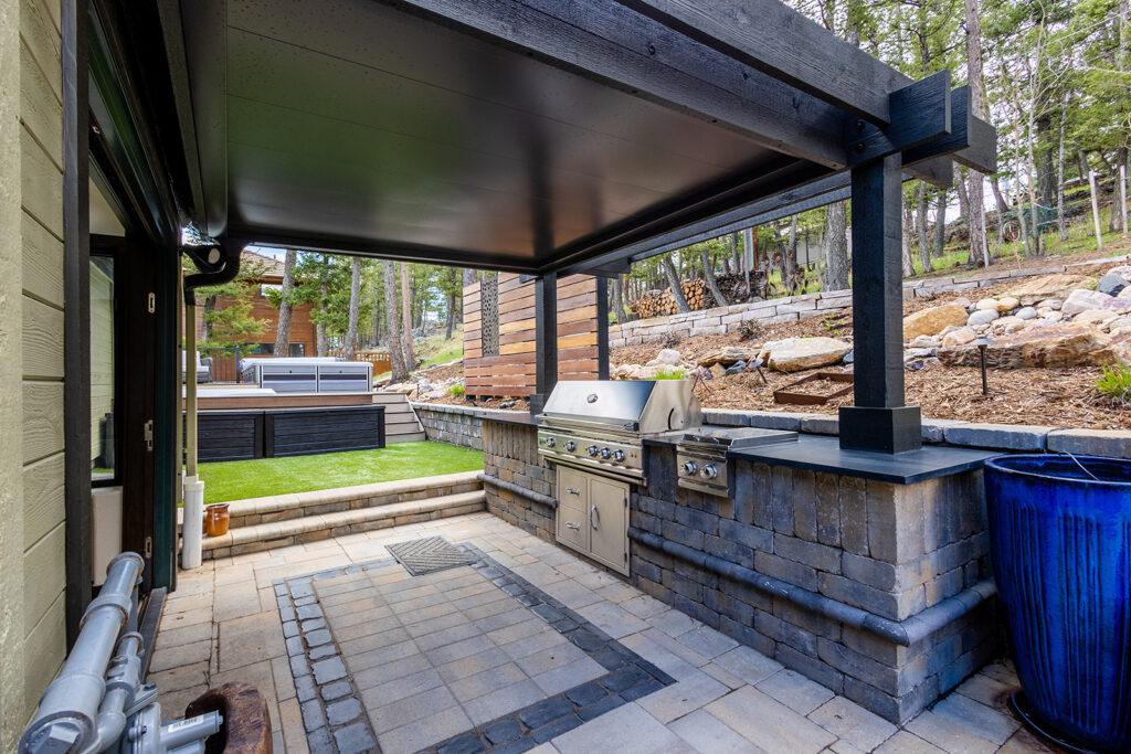 A covered patio with a grill and a hot tub

Description automatically generated