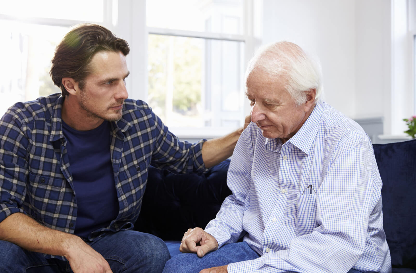 An adult reassuring their parent and rubbing their shoulder during a conversation about moving to assisted living.