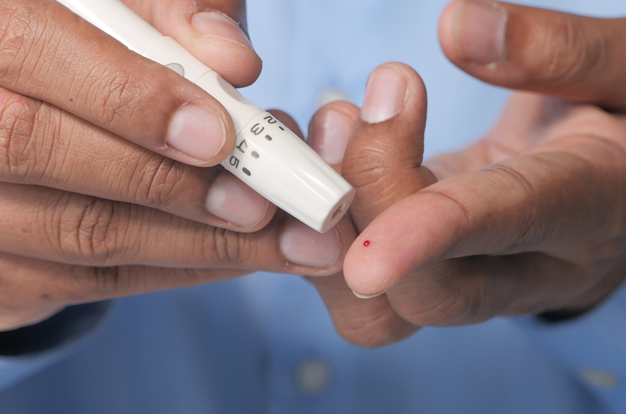 Person testing blood sugar by pricking finger // Healthier Veterans Today