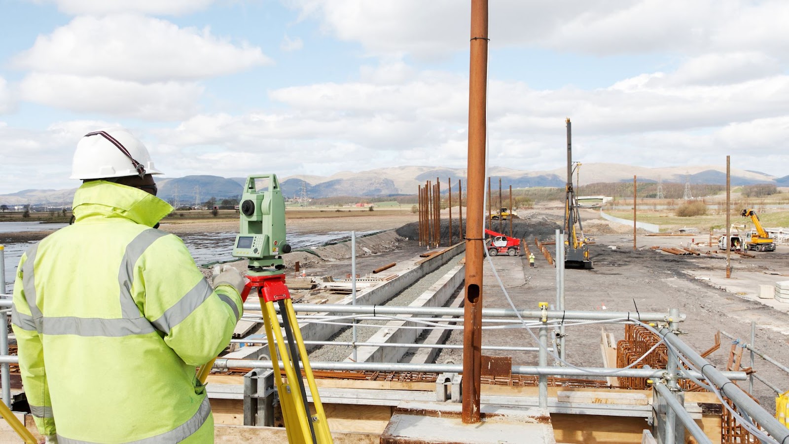 Person standing on a construction site with a surveying device