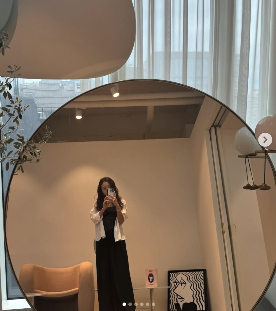 A picture of Former Miss Korea Kim Min Kyung   on a black gown and a white shirt taking a selfie in front of a mirror 