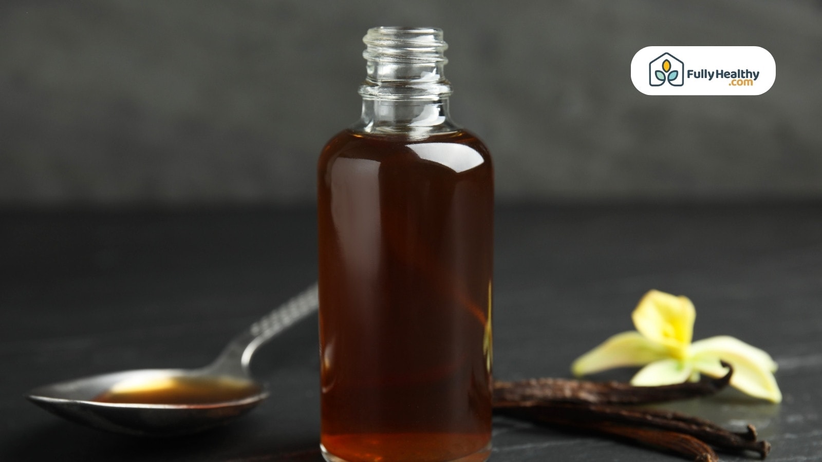 Vanilla extract bottle with spoon vanilla pod and flower on black