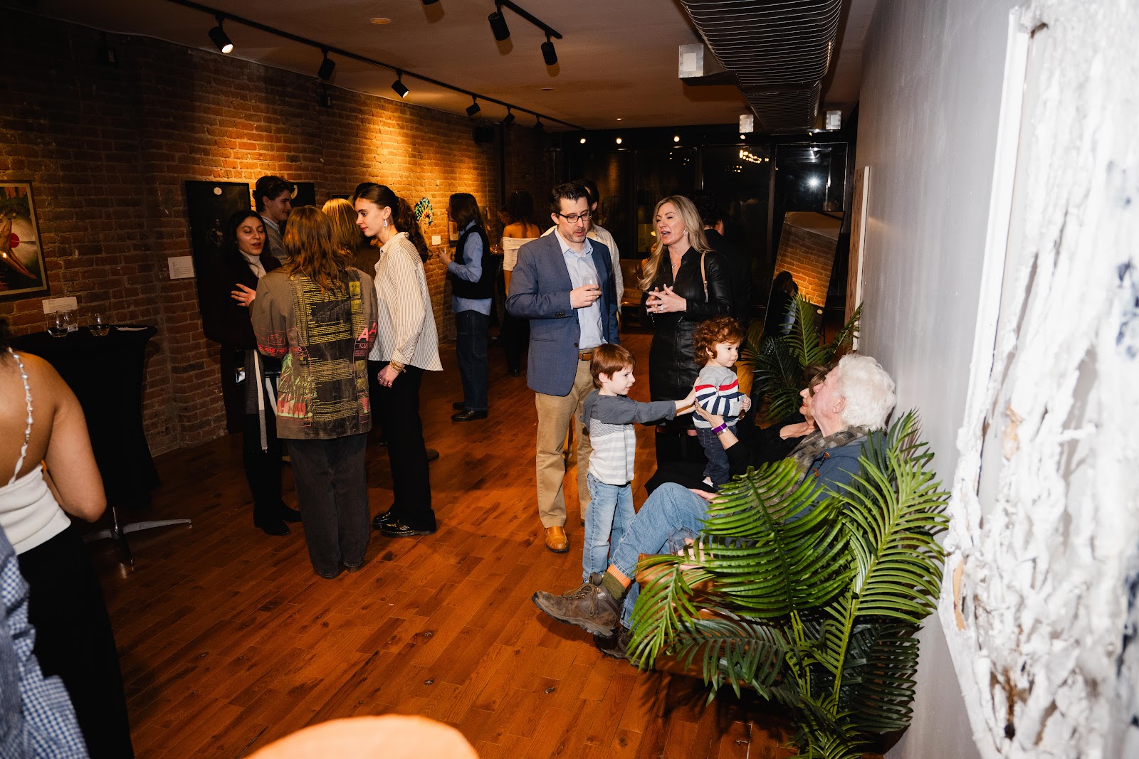 People standing in a dimly lit contemporary space area engaging in conversation. 